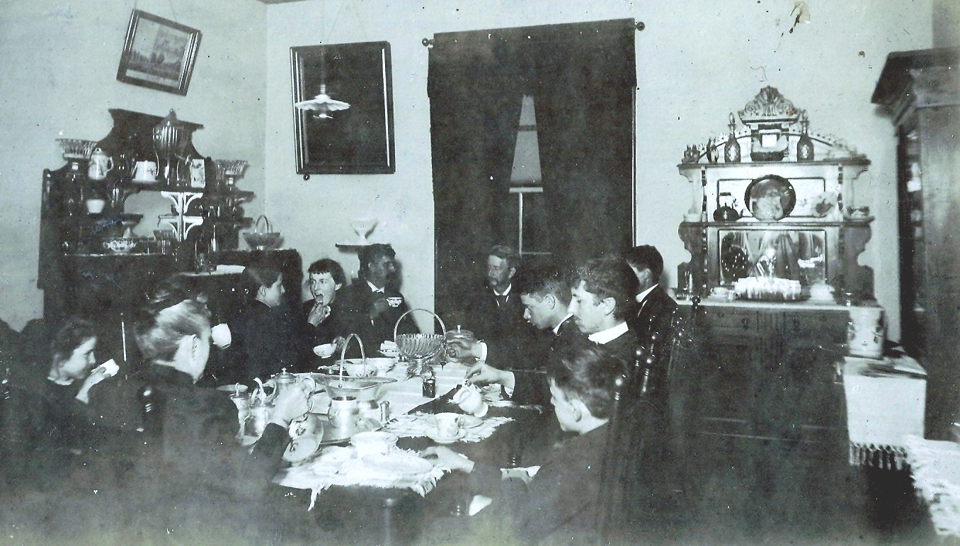 Image of family at dining table in a room with two sideboards and a china cabnet