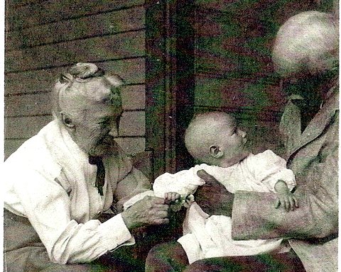 Baby on president's lap with Mrs. McBryde touching his hand.