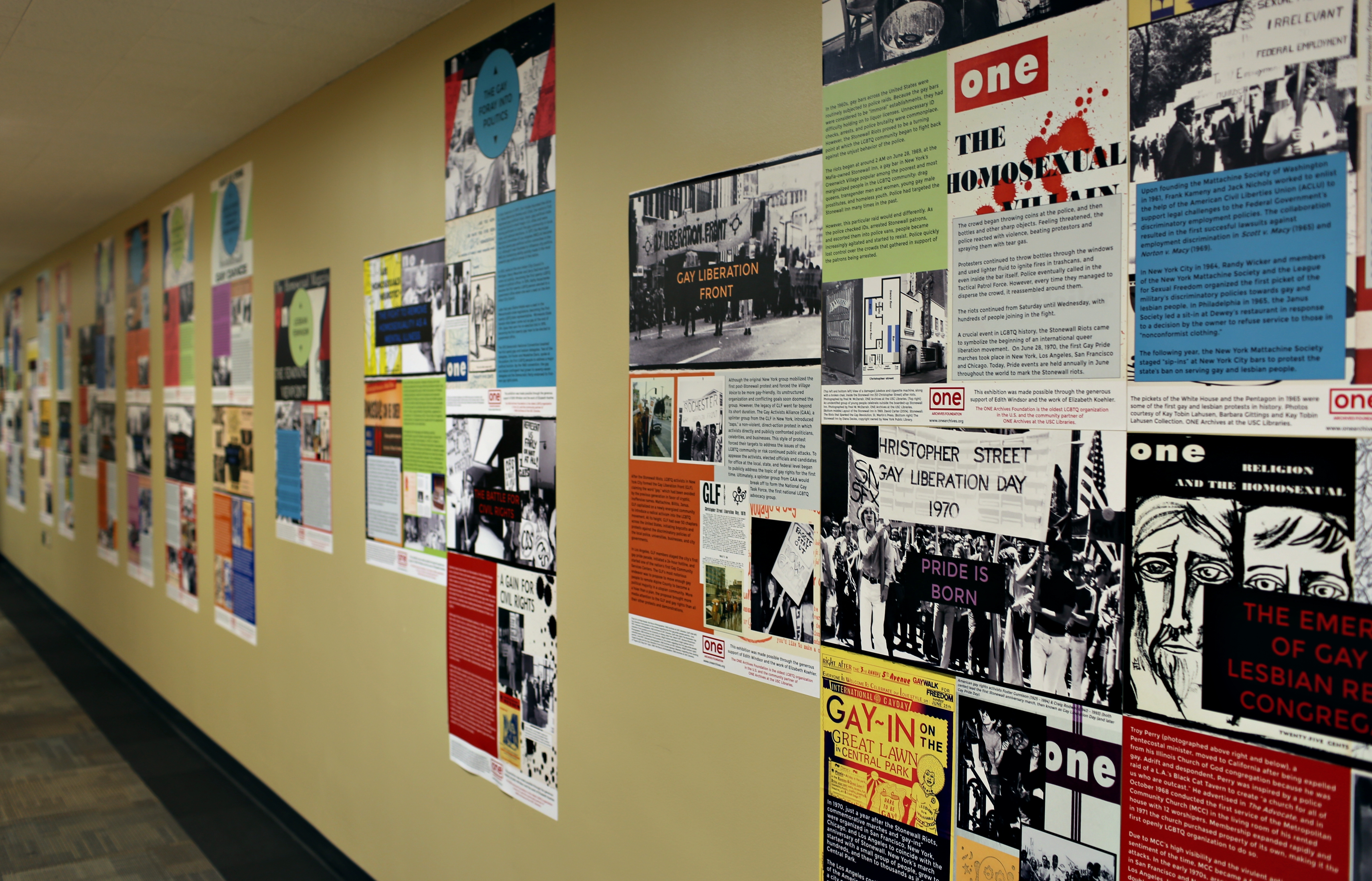 A wide shot photograph showing the History of the LGBTQ Civil Rights Movement exhibit extending down a hallway.