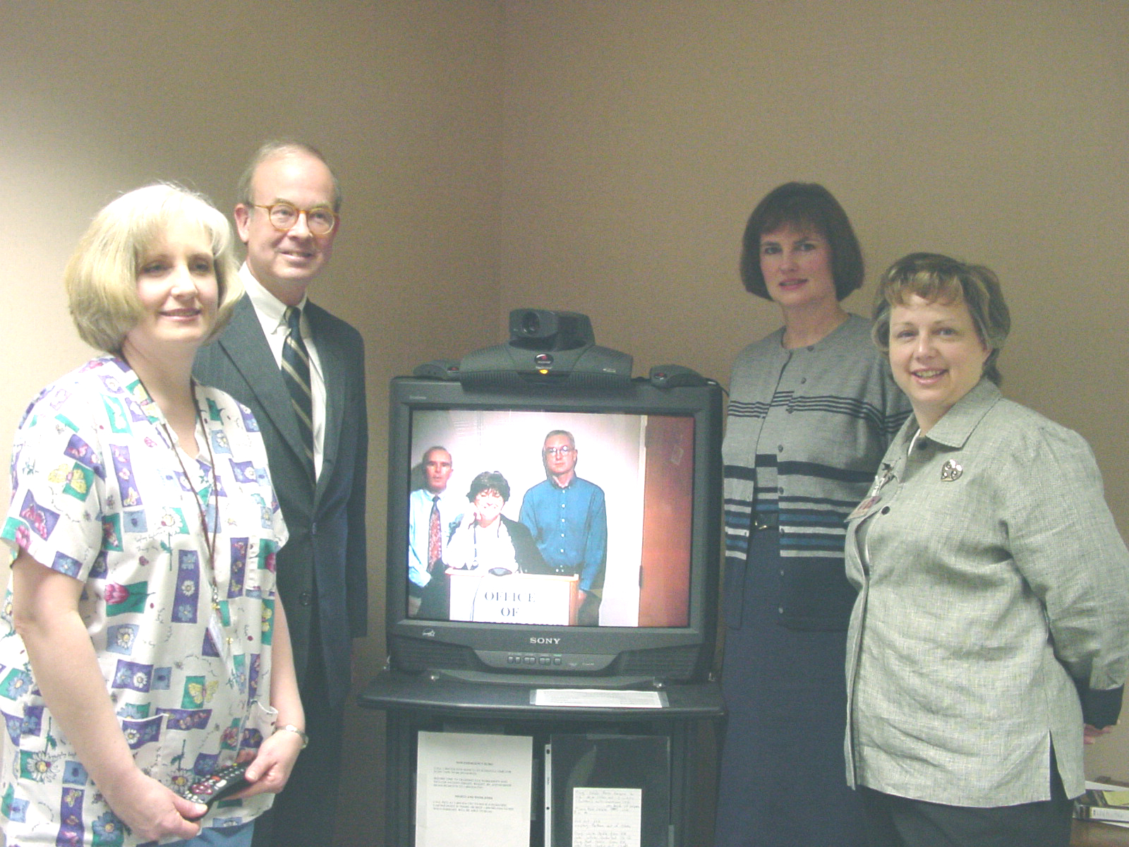 Rick Boucher and group stands next to a television.